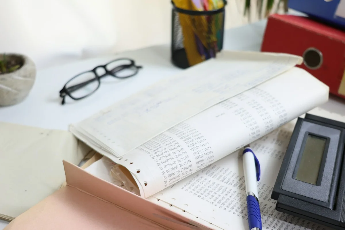 Paper records, glasses, a pen, and a calculator arranged on a desk.